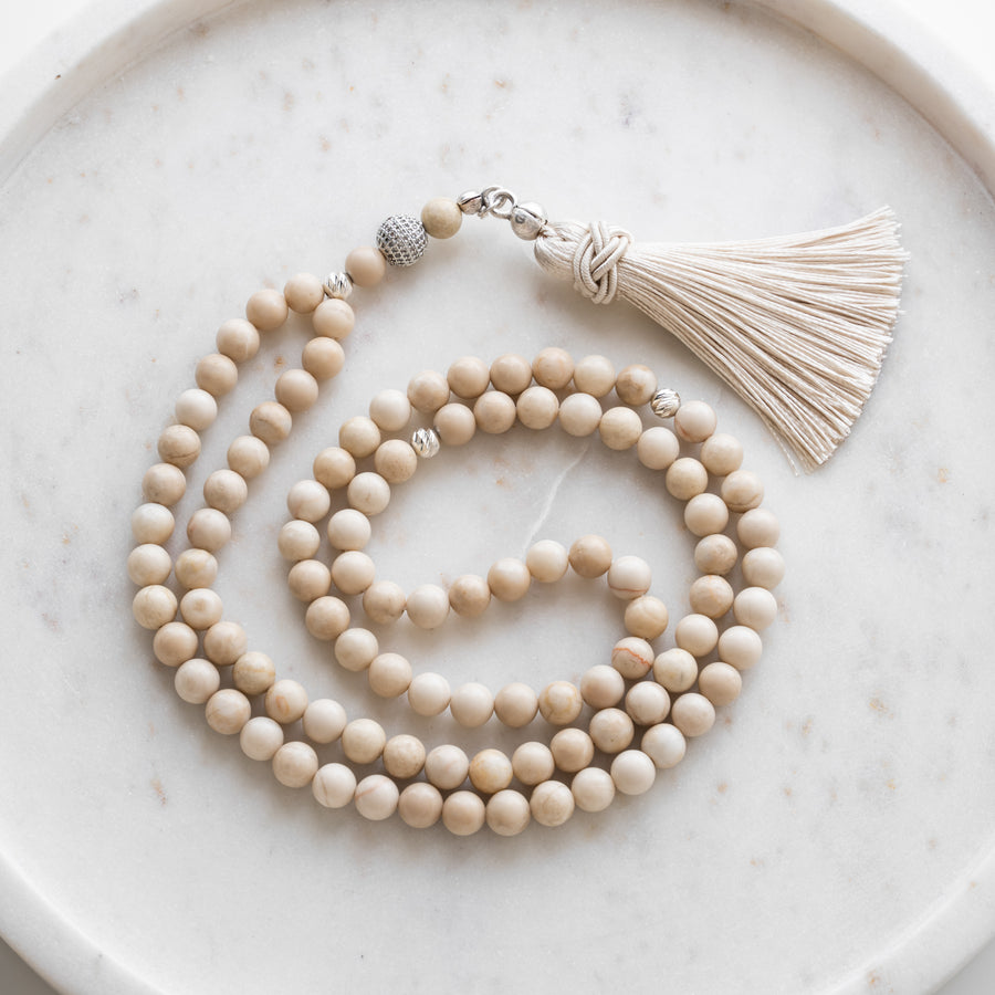 Tasbih (misbaha) i beige kvarts med 99 naturlige perler, skilleperler i sølv og en cremefarvet kvast på hvid marmor