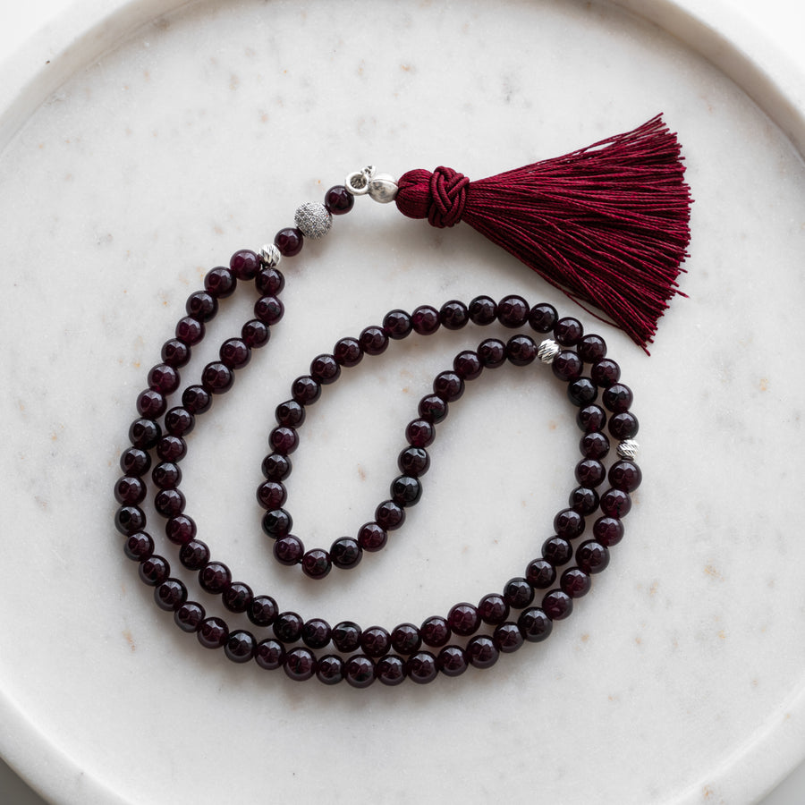 Tasbih (misbaha) i bordeaux kvarts med 99 naturlige perler, skilleperler i sølv og en bordeauxrød kvast på hvid marmor