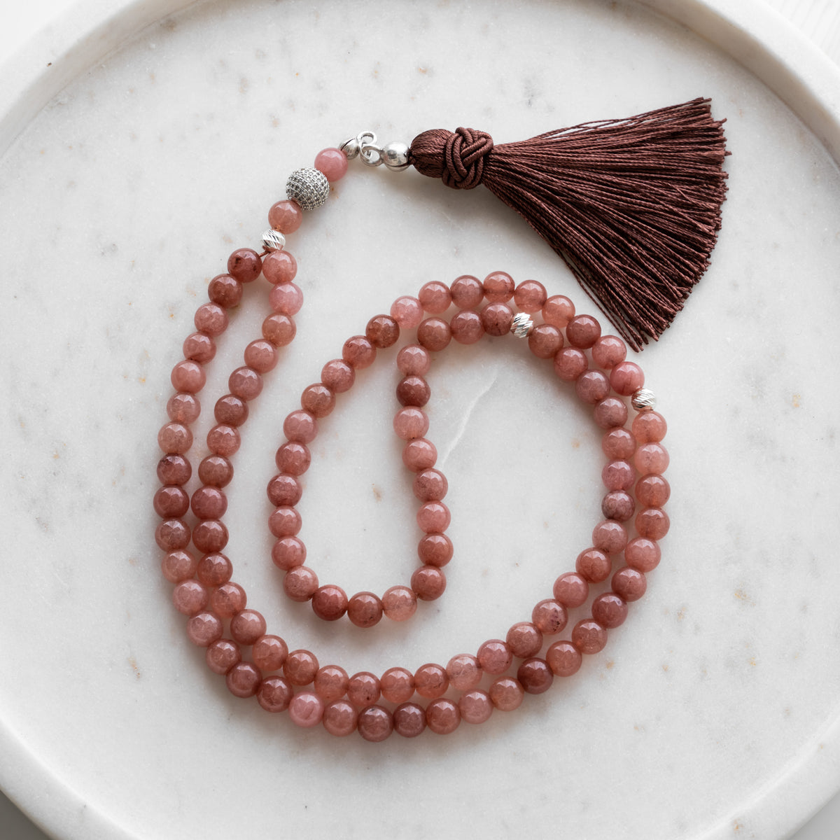 Tasbih (misbaha) i pastelrosa kvarts med 99 naturlige perler, skilleperler i sølv og en brun kvast på hvid marmor