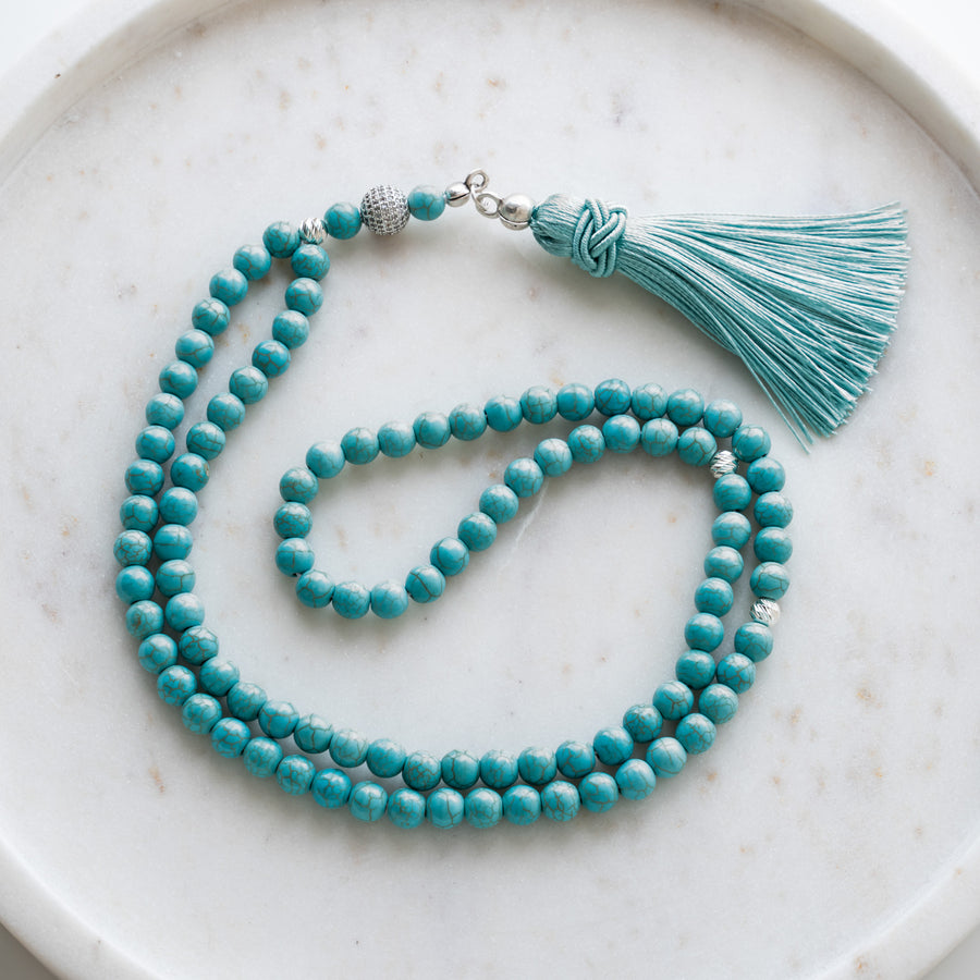 Turquoise tasbih (misbaha) with 99 natural turquoise beads, silver separators and a turquoise tassel on white marble