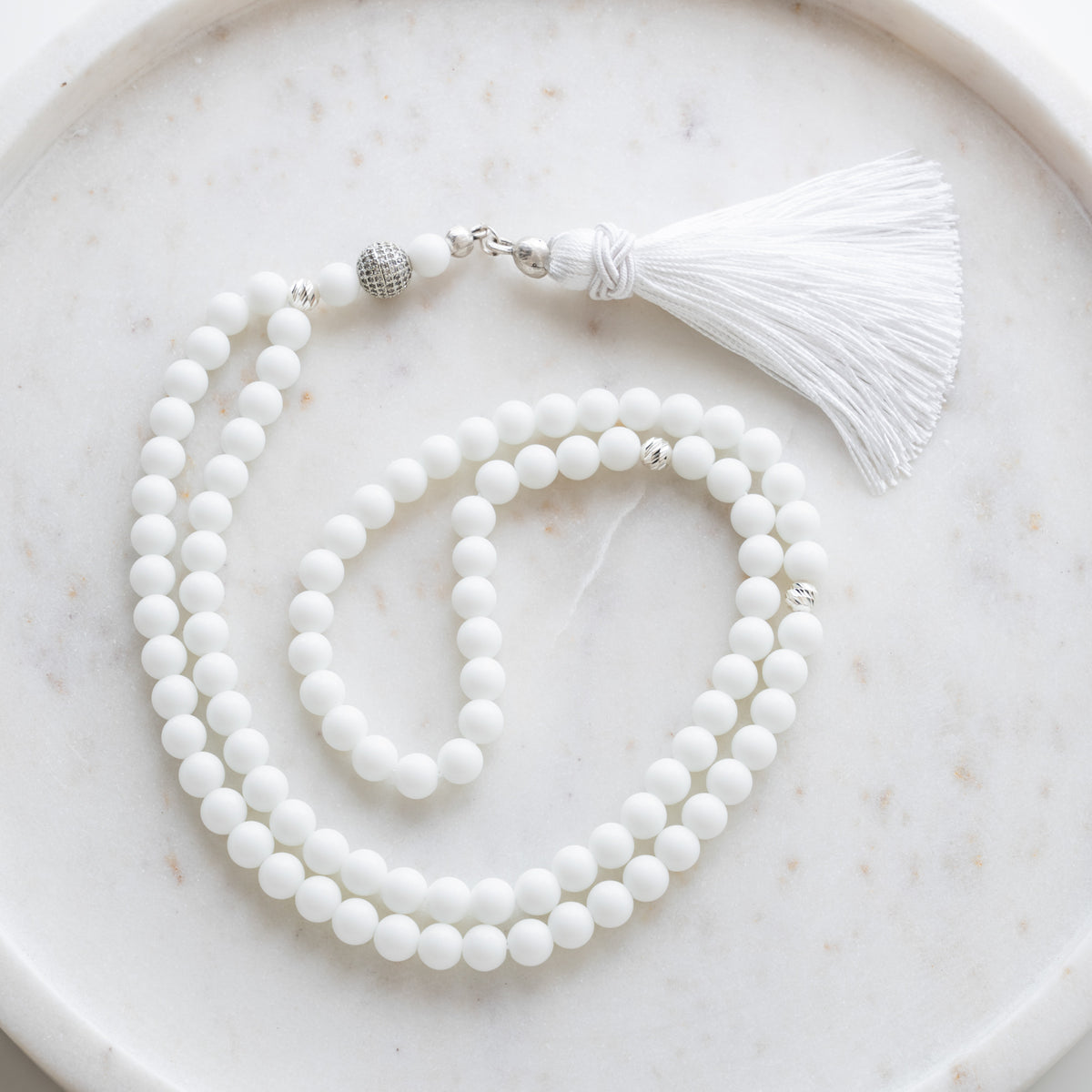 Tasbih (misbaha) i hvid kvarts med 99 naturlige perler, skilleperler i sølv og en hvid kvast på hvid marmor